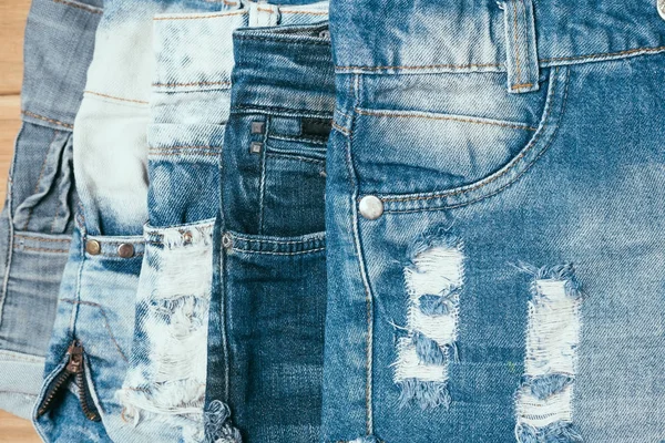 Fashionabla kläder. hög med jeans på en trä bakgrund — Stockfoto