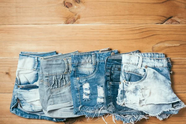 Kvinnliga blå trasiga jeansshorts på gamla trä bakgrund — Stockfoto