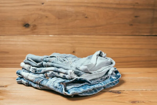 Fashionable clothes. pile of jeans on a wooden background