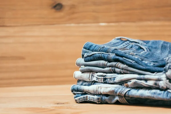 Roupas da moda. pilha de jeans em um fundo de madeira — Fotografia de Stock