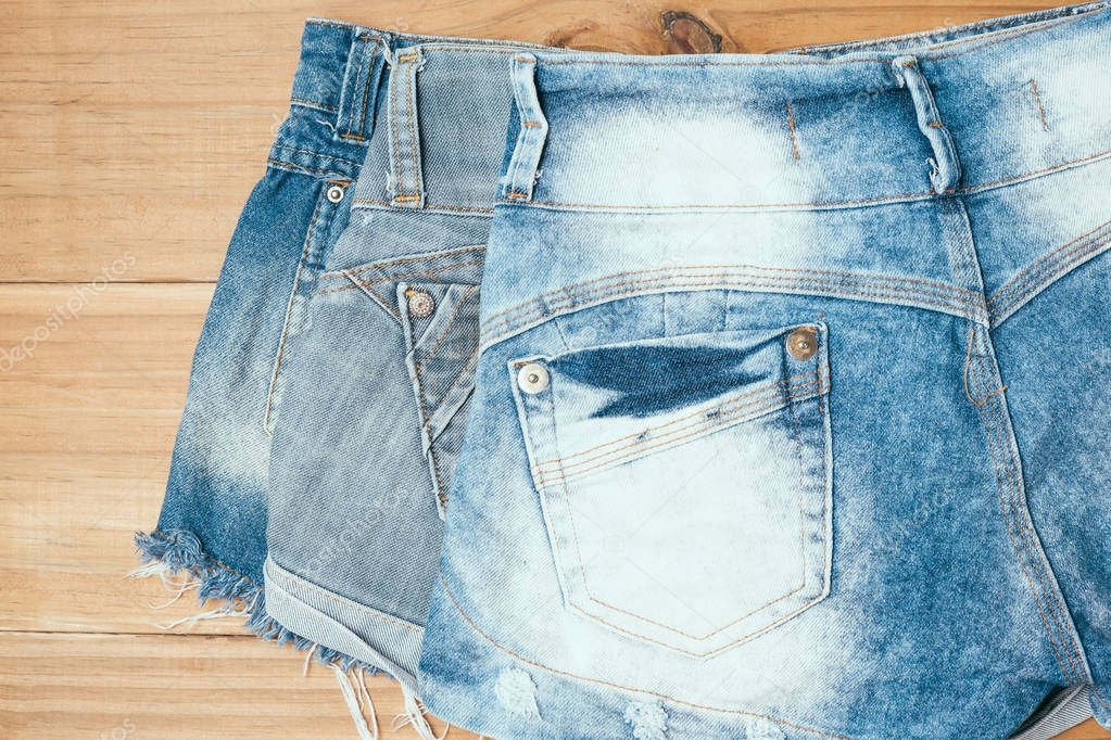 Female blue torn jeans shorts on old wooden background