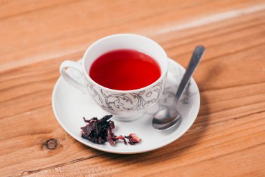 Kırmızı sıcak ebegümeci çayı ahşap bir masa üzerinde bir cam kupa