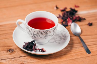 Kırmızı sıcak ebegümeci çayı ahşap bir masa üzerinde bir cam kupa