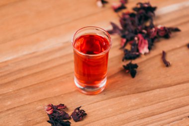 Kırmızı sıcak ebegümeci çayı ahşap bir masa üzerinde bir cam kupa