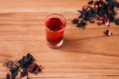 Kırmızı sıcak ebegümeci çayı ahşap bir masa üzerinde bir cam kupa