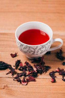 Kırmızı sıcak ebegümeci çayı ahşap bir masa üzerinde bir cam kupa