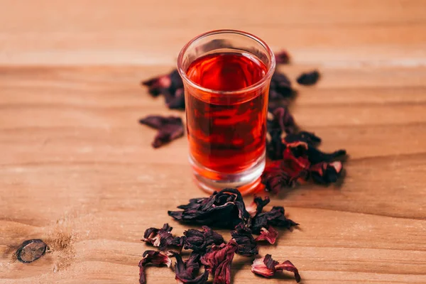 Κόκκινο καυτό hibiscus τσάι σε μια γυάλινη κούπα σε ένα ξύλινο τραπέζι — Φωτογραφία Αρχείου