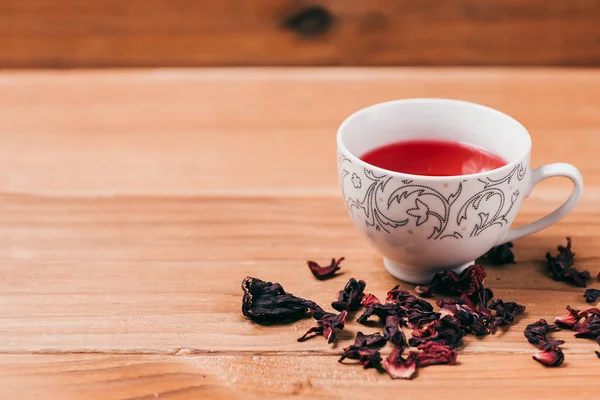 Red hot hibiscus tea in a glass mug on a wooden table