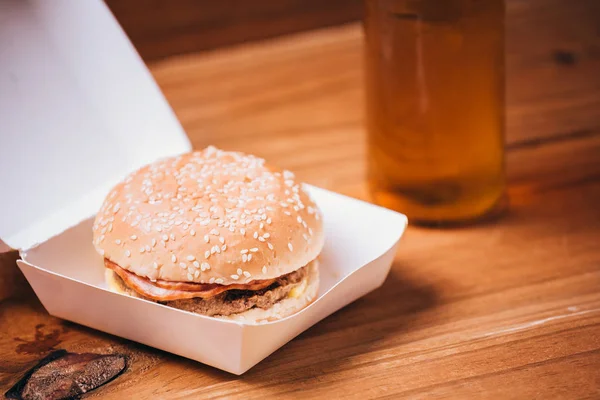 Čerstvé a šťavnaté hamburger a pivo na dřevěné pozadí — Stock fotografie