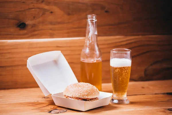 Hambúrguer fresco e suculento e cerveja em fundo de madeira — Fotografia de Stock