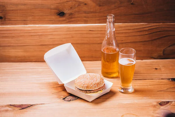 Hambúrguer fresco e suculento e cerveja em fundo de madeira — Fotografia de Stock