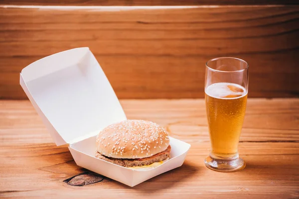 Hambúrguer fresco e suculento e cerveja em fundo de madeira — Fotografia de Stock