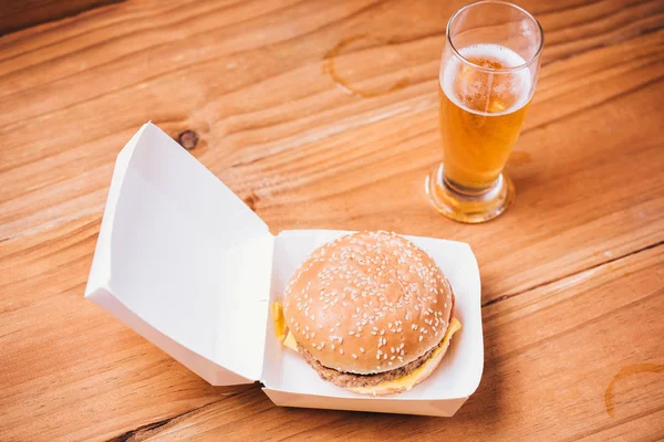 Hambúrguer fresco e suculento e cerveja em fundo de madeira — Fotografia de Stock