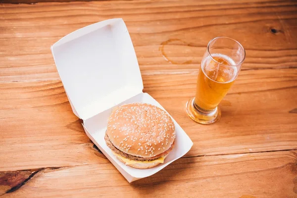 Hambúrguer fresco e suculento e cerveja em fundo de madeira — Fotografia de Stock