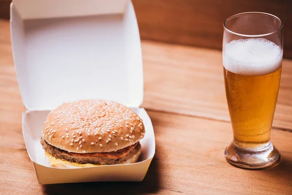 Hambúrguer fresco e suculento e cerveja em fundo de madeira — Fotografia de Stock