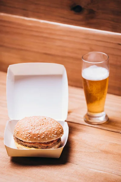 Hambúrguer fresco e suculento e cerveja em fundo de madeira — Fotografia de Stock