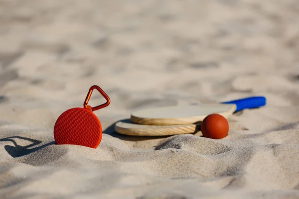 Vezeték nélküli hordozható hangszóró és a strand tenisz ütő a strandon — Stock Fotó