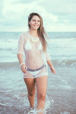 Gün batımında sahilde güzel genç bir kadın.