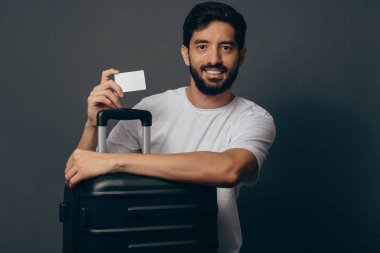 Genç adam seyahat bavul beyaz boş bir kart holding ile portresi