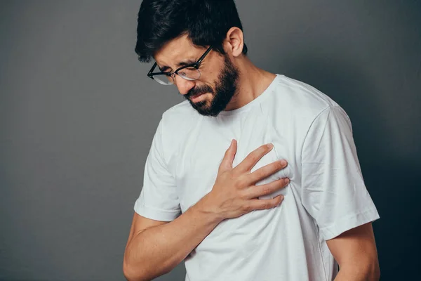 Люди, охорона здоров'я та концепція проблем крупним планом чоловік страждає від серцевого болю на сірому фоні — стокове фото