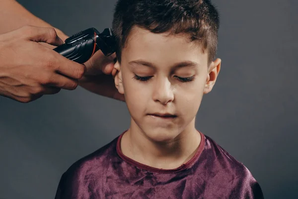 Boy at the barber shop to cut the hair. Cute young boy getting a haircut — Stock Photo, Image