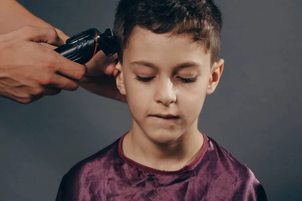 Un chico en la peluquería para cortarle el pelo. Lindo joven recibiendo un corte de pelo — Foto de Stock