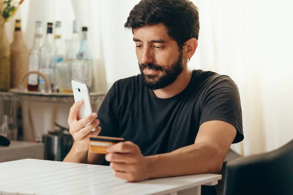 Оплата онлайн. Человек, держащий кредитную карту и использующий смартфон для онлайн-покупок — стоковое фото
