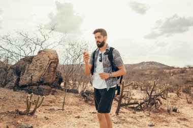 Genç adam gezisinde. Gezgin el akıllı telefon ile dağın günbatımında dinleniyor.