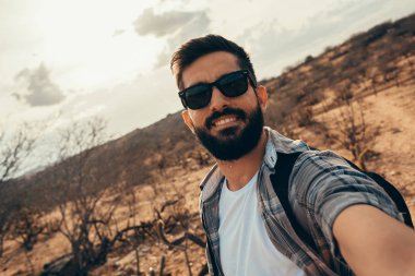 Adam çölde hiking sırt çantası ile seyahat. Seyahat yaşam tarzı başarı kavramı. Kendi portresini yapan erkek