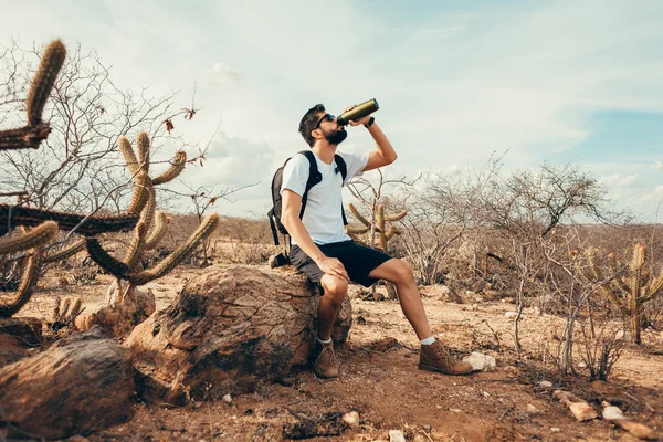 Tired hiker drinks water from a bottle