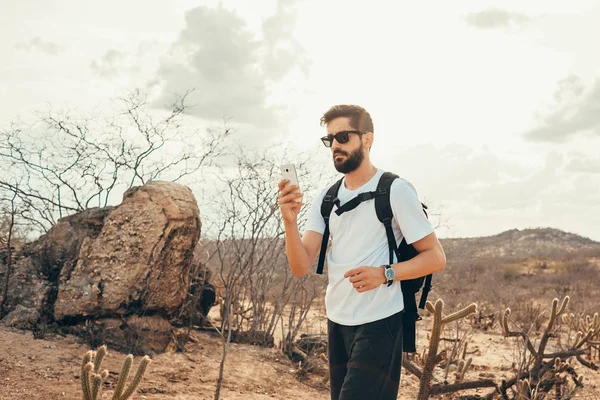 Jonge man op de reis. Reiziger met slimme telefoon in de hand rust op de top van berg bij de zonsondergang. — Stockfoto