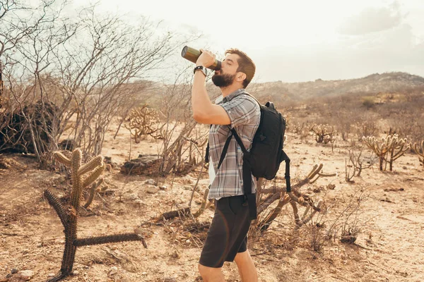 Tired hiker drinks water from a bottle