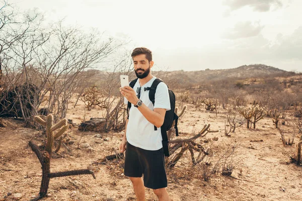 Genç adam gezisinde. Gezgin el akıllı telefon ile dağın günbatımında dinleniyor.