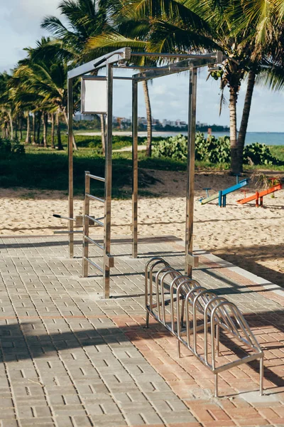 Equipamentos de ginástica gratuitos na praia do Brasil. Imagem diurna do ginásio aberto na praia. Equipamento de fitness instalado para uso público . Fotos De Bancos De Imagens