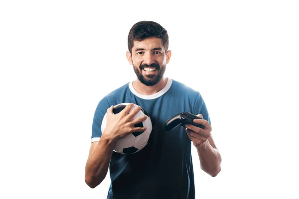 Ποδόσφαιρο ή το ποδόσφαιρο ανεμιστήρα φορώντας μπλε στολή και κρατώντας μια μπάλα και ένα joystick σε λευκό φόντο — Φωτογραφία Αρχείου
