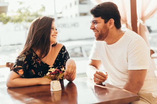 Pasangan muda jatuh cinta duduk di sebuah kafe, mengobrol dan menikmati waktu yang dihabiskan satu sama lain . — Stok Foto