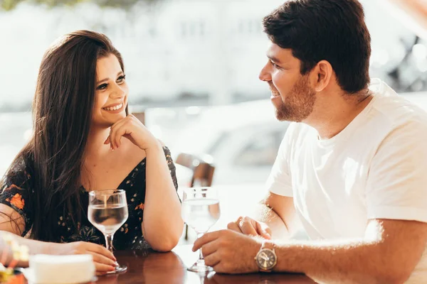 Junges verliebtes Paar sitzt in einem Café, trinkt Wasser, unterhält sich und genießt die Zeit miteinander. — Stockfoto