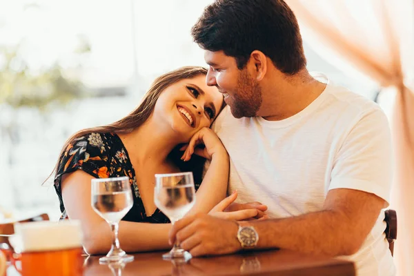 Pareja joven enamorada sentada en un café, bebiendo agua, conversando y disfrutando del tiempo que pasan juntos . — Foto de Stock