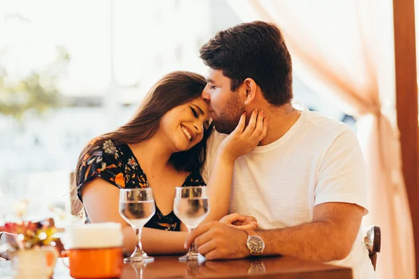 Junges verliebtes Paar sitzt in einem Café, trinkt Wasser, unterhält sich und genießt die Zeit miteinander. — Stockfoto