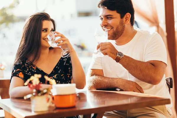 Junges verliebtes Paar sitzt in einem Café, trinkt Wasser, unterhält sich und genießt die Zeit miteinander. — Stockfoto