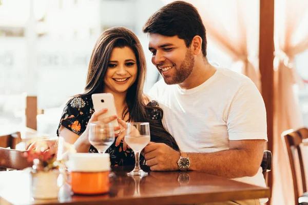 Paar im Restaurant schaut auf sein Smartphone — Stockfoto