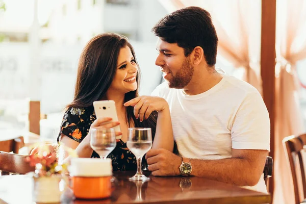 Paar im Restaurant schaut auf sein Smartphone — Stockfoto