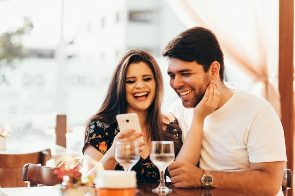 Paar in restaurant zijn slimme telefoon kijken — Stockfoto