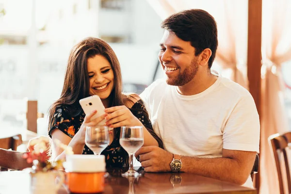 Pasangan di restoran melihat telepon pintarnya — Stok Foto