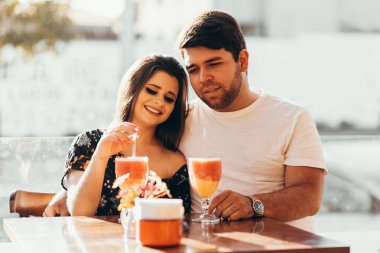 Genç çift aşık bir restoranda oturan renkli içki içme, konuşma ve vaktinizi birbirleri ile geçirdi