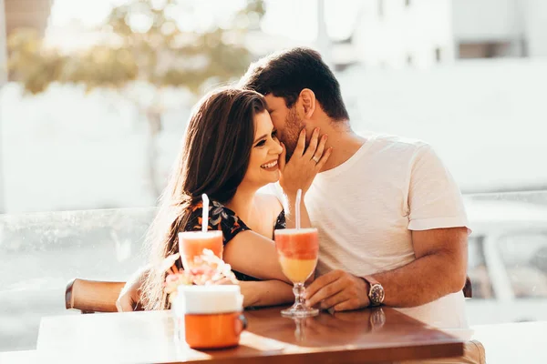 Pareja joven enamorada sentada en un restaurante, bebiendo bebida colorida, conversando y disfrutando del tiempo pasado juntos — Foto de Stock