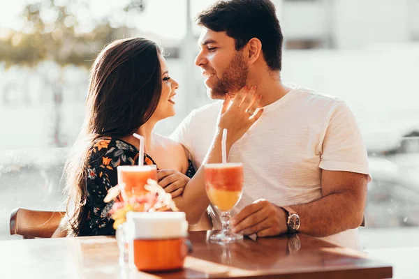 Junges verliebtes Paar sitzt in einem Restaurant, trinkt ein buntes Getränk, unterhält sich und genießt die Zeit miteinander — Stockfoto