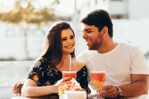 Jovem casal apaixonado sentado em um restaurante, bebendo bebida colorida, tendo uma conversa e aproveitando o tempo passado uns com os outros — Fotografia de Stock