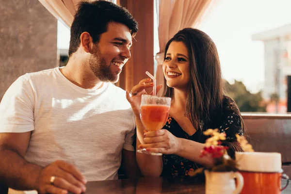 Young couple in love sitting in a restaurant, drinking colorful drink, having a conversation and enjoying the time spent with each other — Stock Photo, Image