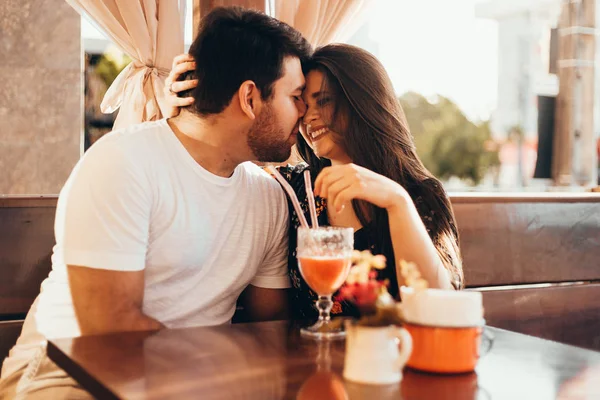 Junges verliebtes Paar sitzt in einem Restaurant, trinkt ein buntes Getränk, unterhält sich und genießt die Zeit miteinander — Stockfoto